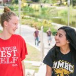 two female students enjoying summer day on UMBC campus hill